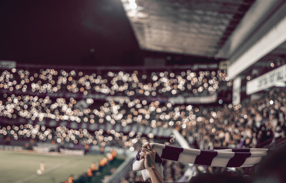 The Teamstore logo over a crowd in soft focus with a club scarf held up