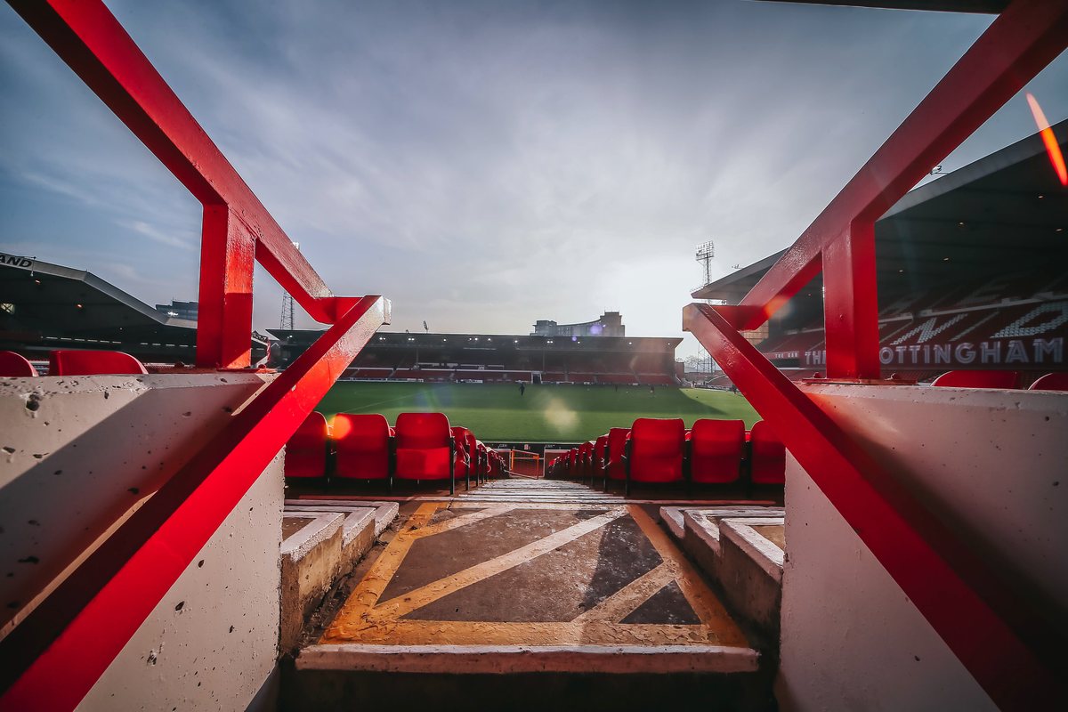 red seating and steelwork framing a view of the pitch